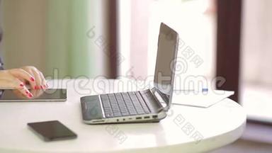 一名女学生正在咖啡馆里的笔记本电脑上工作，并在平板电脑上浏览图片。 右起全景